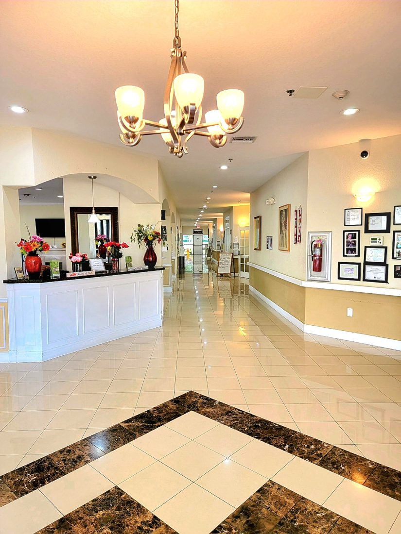 Reception desk and entry hall under a chandelier at Sunny Hills in Homestead